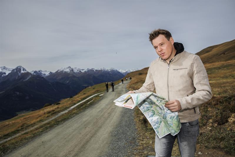 Sven Berchtold in un sentiero di montagna con una cartina geografica